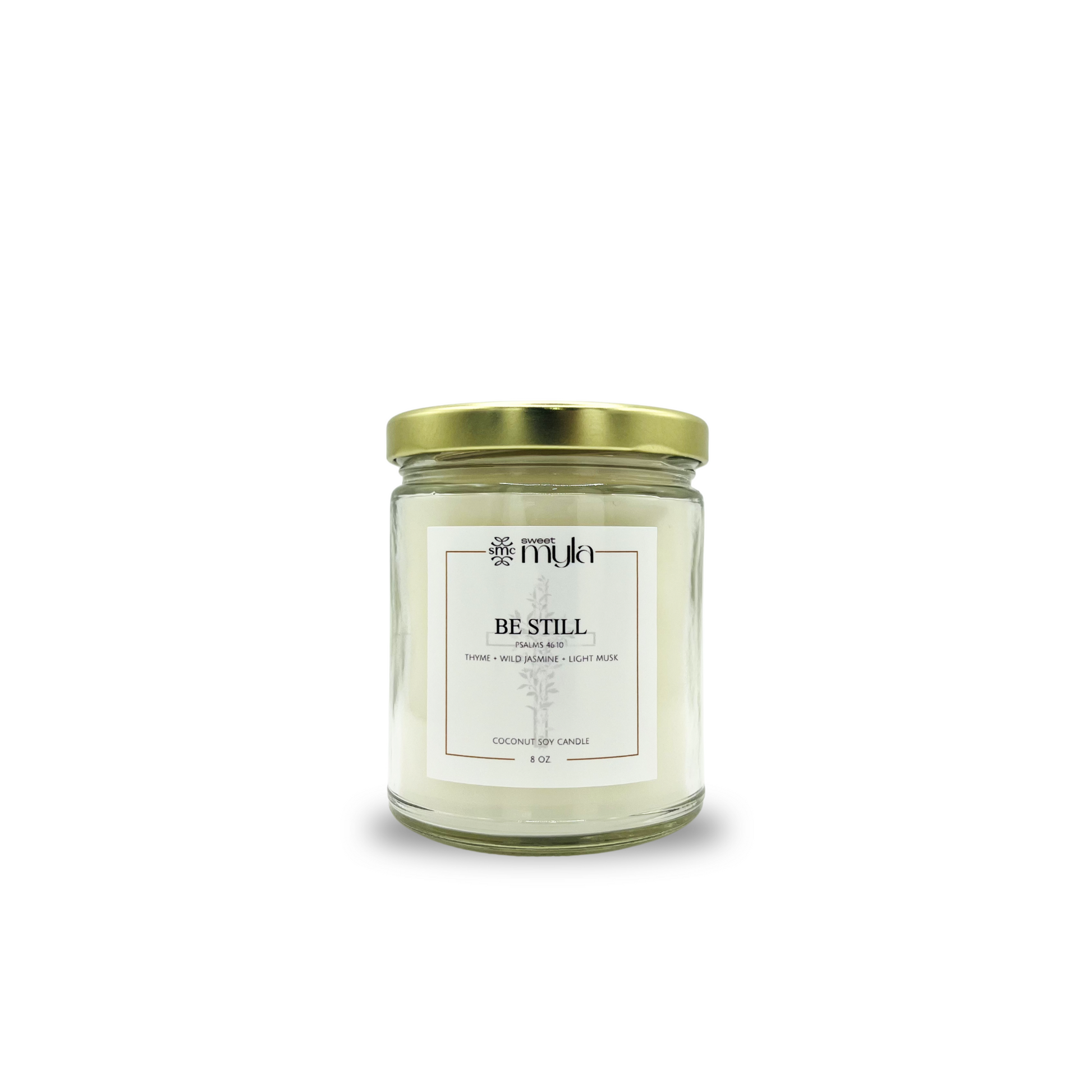 Candle jar with a gold lid labeled 'Be Still' on a white background