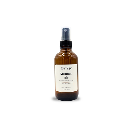 An amber glass spray bottle with a black spray nozzle and a cream-colored label reading 'Autumn Air' on a plain white background by Sweet Myla. 