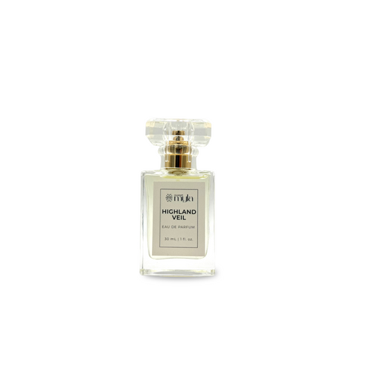 A rectangular clear perfume bottle with a clear faceted cap and a gold collar, featuring a white label that reads 'HIGHLAND VEIL EAU DE PARFUM'.