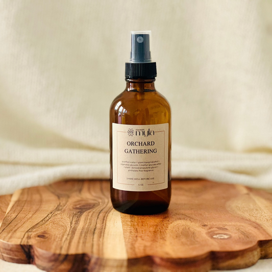 Amber glass spray room and linen bottle labeled Orchard Gathering.