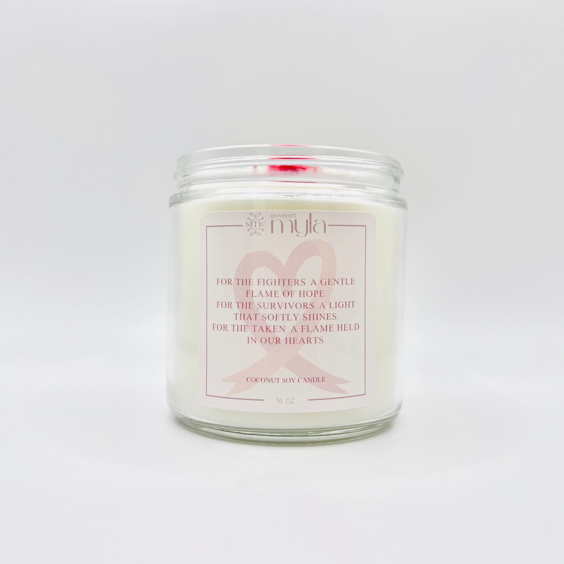Candle in a glass jar with a label and a cancer awareness ribbon on a white background