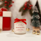Candle jar with a red ribbon labeled 'Midnight Blessings' in a festive setting with Christmas decorations.