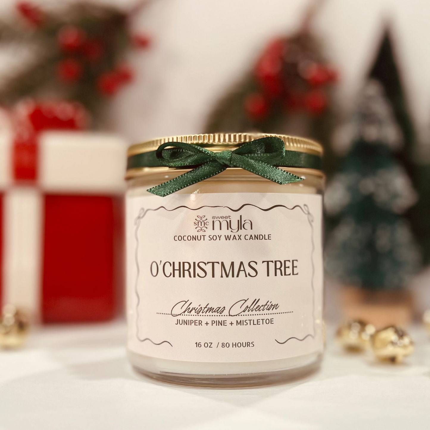 Coconut soy wax candle labeled 'O' Christmas Tree' with a green ribbon against a blurred festive background.