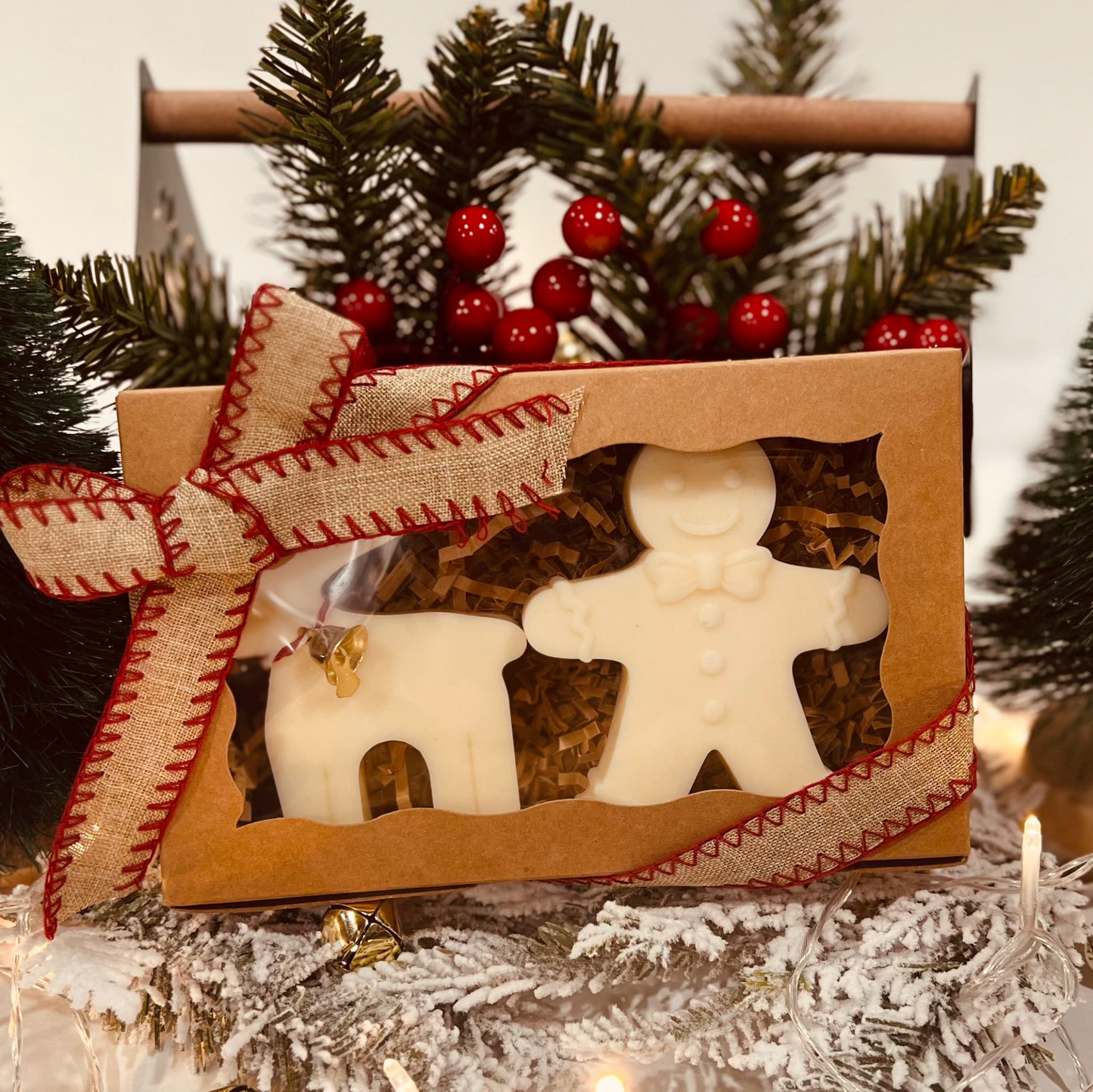 Decorative gingerbread man and reindeer wax melt/candle set in a box with Christmas trees in the background.