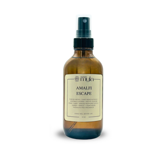 Amber colored room + linen spray bottle labeled 'Amalfi Escape' on a white background